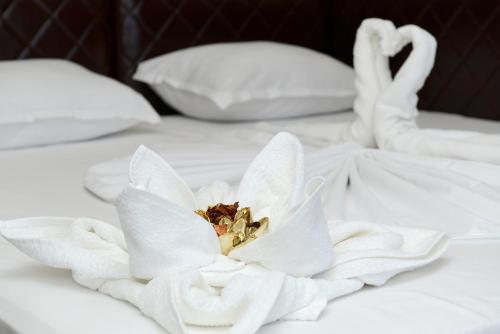 a white flower on a white bed with pillows at Diamond Kiten in Kiten