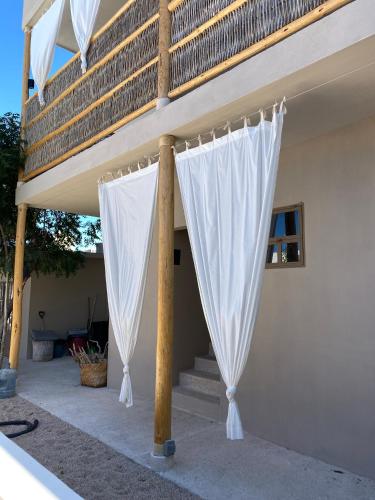 a porch with white curtains on the side of a house at The Mantarraya Outpost in La Paz