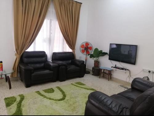 a living room with black leather furniture and a flat screen tv at Che Na Homestay Pontian in Pontian Kecil