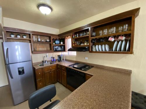 a kitchen with a stainless steel refrigerator and wooden cabinets at Casita Capri in Ciudad Juárez