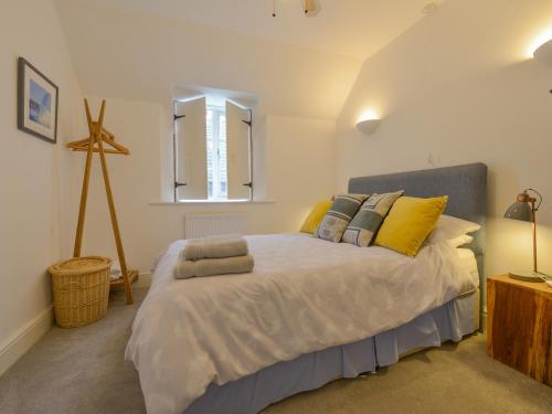 a bedroom with a bed with yellow and gray pillows at The Old Post Office in Turnchapel