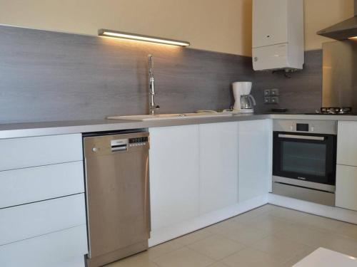 une cuisine avec des armoires blanches et un évier dans l'établissement Appartement climatisé 3 pièces, 6 couchages, proche plage et centre, garage inclus - FR-1-250-61, au Grau-du-Roi