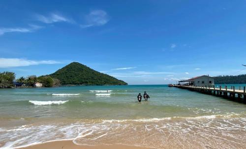 two people standing in the water near a pier at CocoHuts in Koh Rong Sanloem