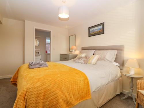 a bedroom with a large bed with an orange blanket at Cae Glas in Pwllheli