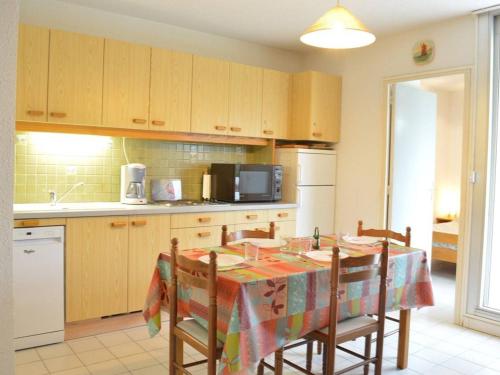 une cuisine avec une table avec des chaises et un micro-ondes dans l'établissement Appartement cosy 6 pers avec parking, proche plage et commerces - Le Grau du Roi - FR-1-250-105, au Grau-du-Roi