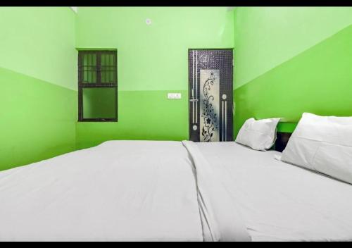 Habitación verde con cama blanca y puerta en Dev Guest House By WB Inn en Agra
