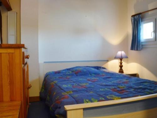 une chambre avec un lit avec une couette bleue et une fenêtre dans l'établissement Pavillon 2 pièces avec mezzanine, 6 couchages, terrasse, piscine, proche plage - Narbonne Plage - FR-1-229B-45, à Narbonne