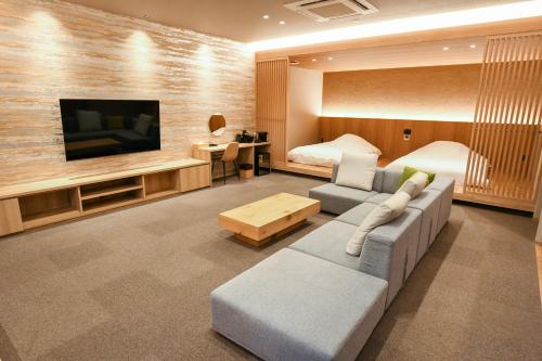 een woonkamer met een bank en een tv bij Sozankyo in Aso