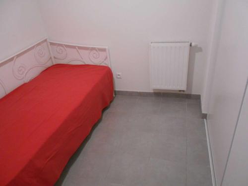 une petite chambre avec un lit rouge et un radiateur dans l'établissement Appartement T2 Cabine Climatisé, Terrasse, Parking Privé, Au Grau-du-Roi, Proche Plage et Centre - FR-1-250-175, au Grau-du-Roi