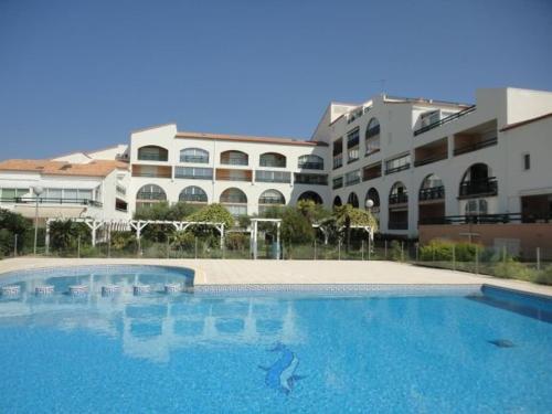 une grande piscine devant un immeuble dans l'établissement Appartement duplex 3 pièces avec piscine, climatisation et garage à Port Camargue - FR-1-250-192, au Grau-du-Roi