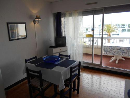 une salle à manger avec une table et des chaises et une grande fenêtre dans l'établissement Appt climatisé 4 pers avec parking à Port Camargue - FR-1-250-206, au Grau-du-Roi