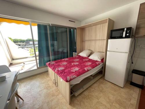 - une petite chambre avec un lit et un réfrigérateur dans l'établissement Studio climatisé 4 pers avec piscine et parking à Port Camargue - FR-1-250-230, au Grau-du-Roi