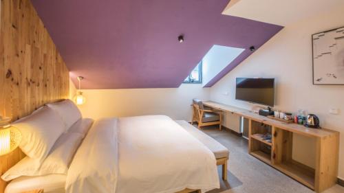 a bedroom with a bed and a desk with a tv at Yunshan Villa in Huangshan Scenic Area