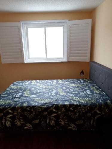 1 dormitorio con 1 cama con edredón azul y ventana en Fancy home in Richmond hill, en Richmond Hill