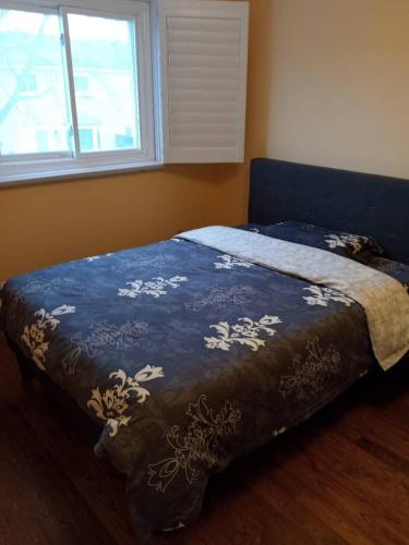 a bedroom with a bed with a blue blanket and a window at Fancy home in Richmond hill in Richmond Hill