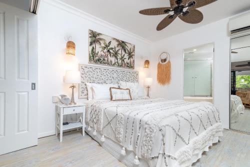 a white bedroom with a bed and a ceiling fan at Luxury Living In The Heart Of Town, King Bed, 2 Pools, Free WIFI And Undercover Parking in Port Douglas
