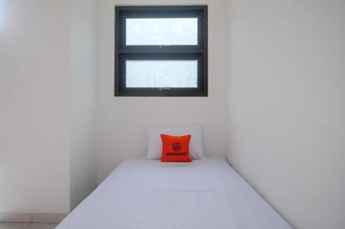 a red pillow on a bed in a room with a window at KoolKost near Kampus UNS Solo (Minimum Stay 6 Nights) in Solo
