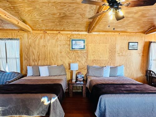 1 dormitorio con 2 camas y ventilador de techo en Country Cabins Hotel, en Chariton