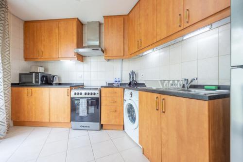 a kitchen with wooden cabinets and a washer and dryer at Luxury Escapes - Tranquil Retreat - Studio Apts near Metro and Mall - Discovery Gardens - SHAR & MCL in Dubai