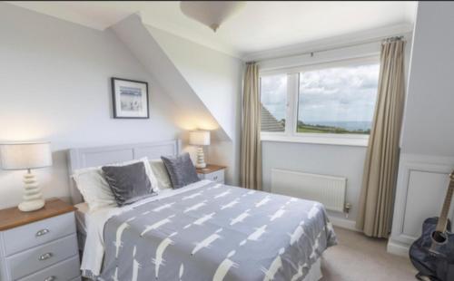 a bedroom with a bed and a large window at Halekulani Devon Homestay in Torquay