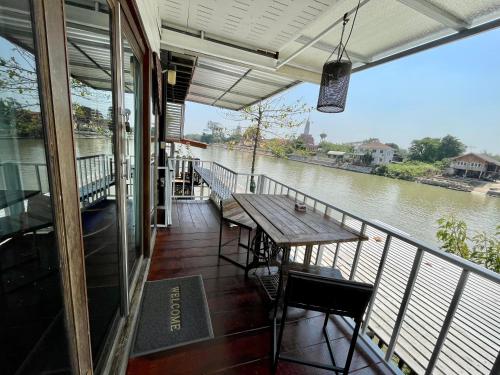 a balcony with a table and chairs and a river at Baan Keang Chon Ayutthaya บ้านเคียงชล อยุธยา in Phra Nakhon Si Ayutthaya