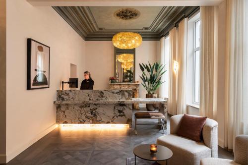 a woman standing in a living room with a fireplace at Dukes' Academie Brugge in Bruges