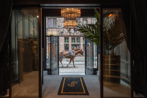 a door with a horse walking into a building at Dukes' Academie Brugge - by Dukes' Hotel Collection in Bruges