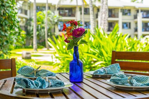 a table with a blue vase with a flower in it at Turtle Bay Villas 205 in Kahuku