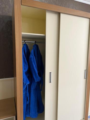 a closet with blue jackets hanging in it at Almaty Grand Erbil Hotel in Almaty