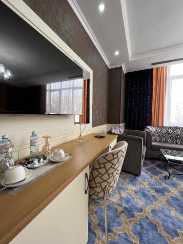 a room with a counter and a living room at Almaty Grand Erbil Hotel in Almaty
