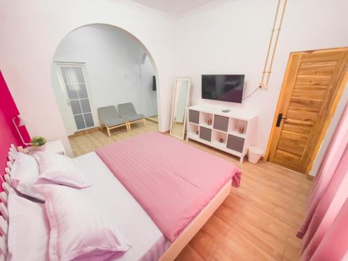 ein Schlafzimmer mit einem großen Bett mit einer rosa Decke in der Unterkunft OsOs Paviliun in Timuran