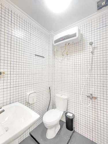a white bathroom with a toilet and a sink at OsOs Paviliun in Timuran