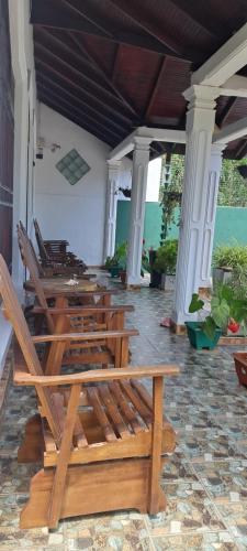 a row of wooden benches sitting on a porch at Indunil place hiriketiya in Dickwella