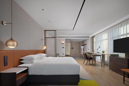a bedroom with a large white bed and a desk at Home2 Suites by Hilton Guiyang Nanming Jiyuan in Guiyang