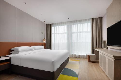 a hotel room with a bed and a flat screen tv at Home2 Suites by Hilton Guiyang Nanming Jiyuan in Guiyang