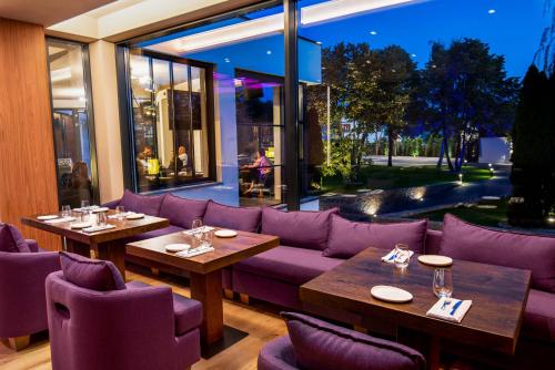 a restaurant with purple furniture and tables and windows at Hotel Stein Collection in Timişoara