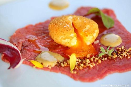 a piece of meat with sauce and nuts on a white plate at Relais Bella Rosina Pool & Spa in Fiano
