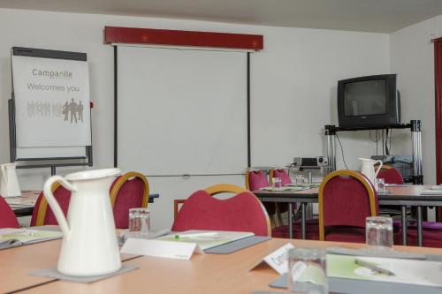 a conference room with a table and chairs and a screen at Campanile Hotel - Basildon - East of London in Basildon