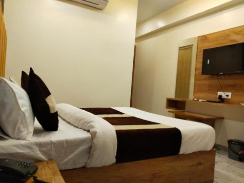 a hotel room with a bed and a television at Hotel Skyland in Ahmedabad