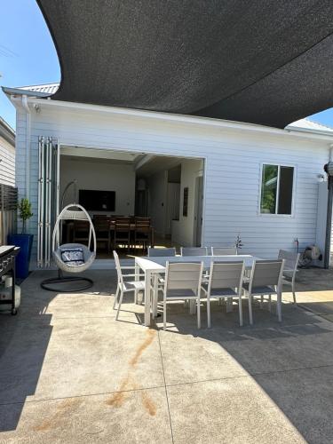 um pátio com uma mesa branca e cadeiras numa casa em Garden Cottage em Geelong