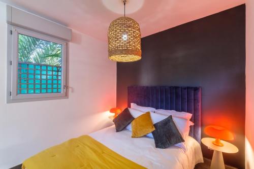 sypialnia z łóżkiem, oknem i żyrandolem w obiekcie Villa Elena - Studio proche plage avec terrasse w Cannes