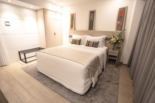 a white bedroom with a large white bed with pillows at Sarova Imperial Hotel in Kisumu