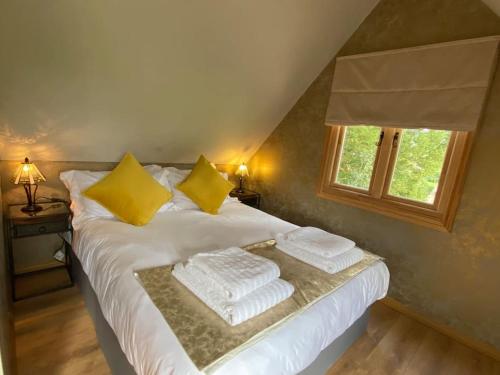 a bedroom with a white bed with yellow pillows and a window at Lodge House in Grounds of Victorian Country Estate in Taunton
