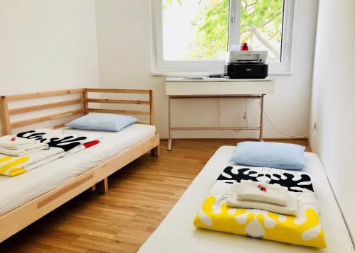 um quarto com 2 camas, uma secretária e uma janela em Cozy Danube Room - 15 mins to Downtown em Viena