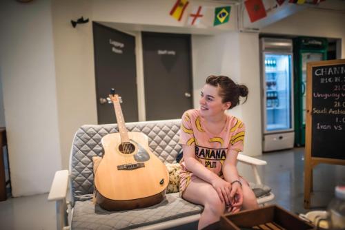 a woman sitting on a couch with a guitar at Jam Hostel Bangkok in Bangkok