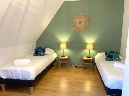 コルマールにあるGîte "Schongauer" hypercentre Colmarのベッド2台、テーブル2台、ランプ2つが備わる客室です。