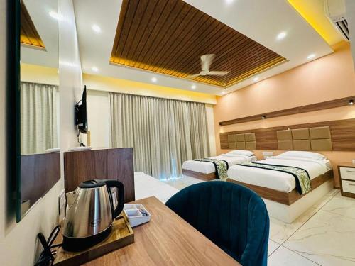 a hotel room with two beds and a desk and a table at Aananda Wellness and Resorts in Dharmastala