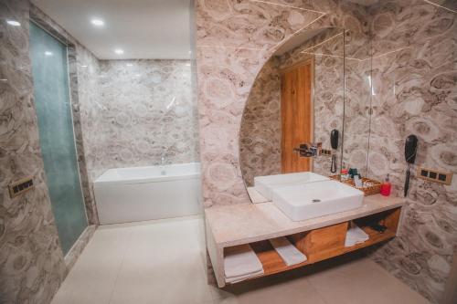 a bathroom with a sink and a bath tub at Hotel Mirana , Tinsukia in Tinsukia