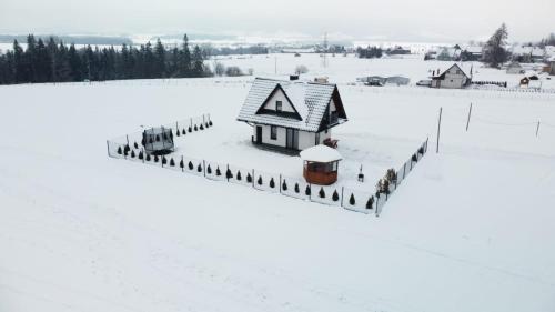 a house covered in snow in a field at Domek u Zbyszka in Groń