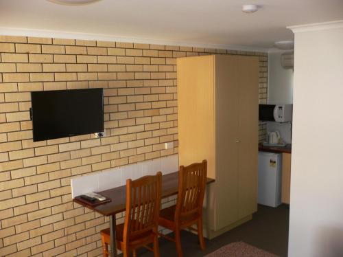a room with a table and a tv on a brick wall at Goomeri Motel in Goomeri